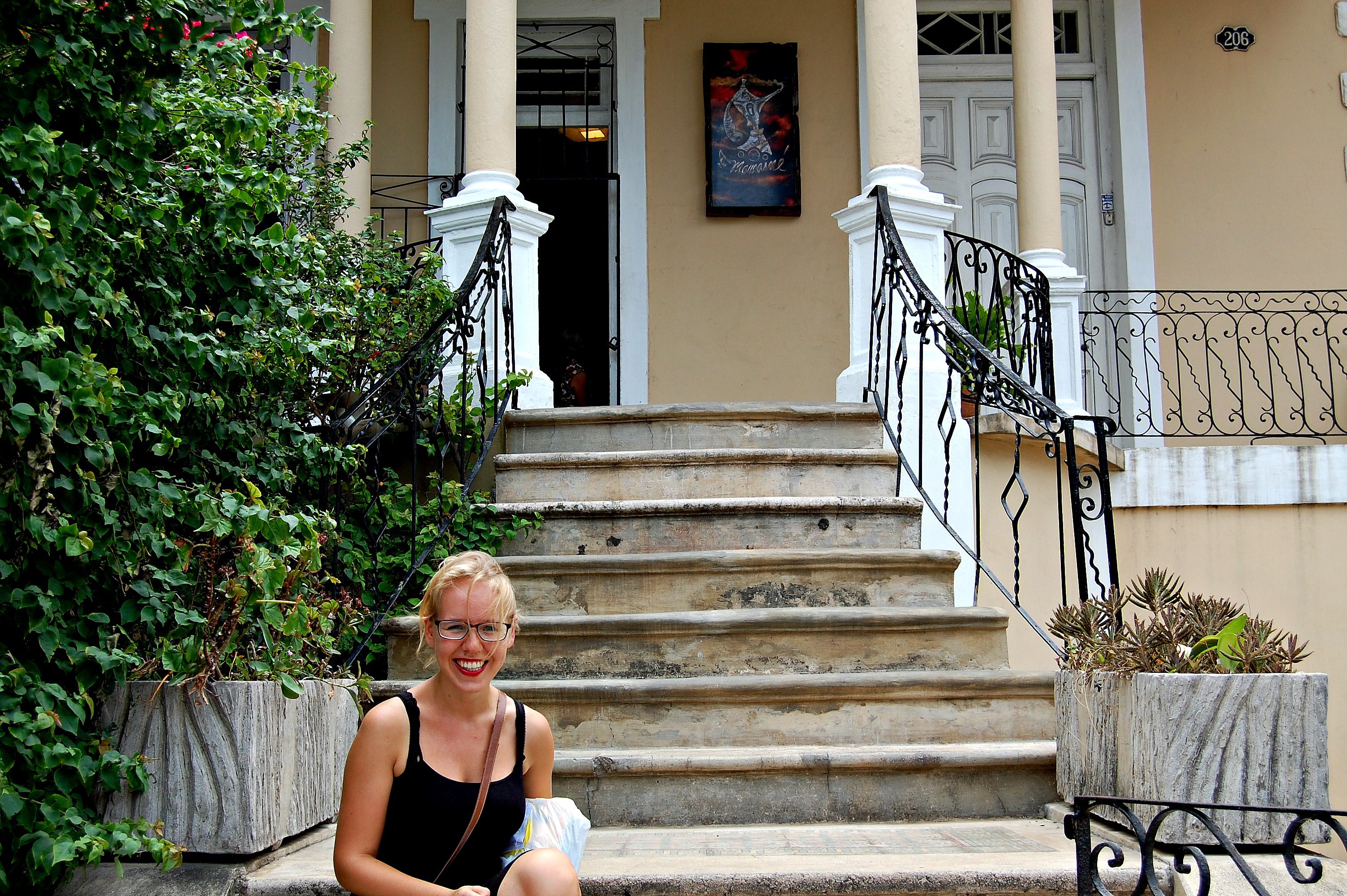 Woman sitting in front of old mansion in Vedado, Havana