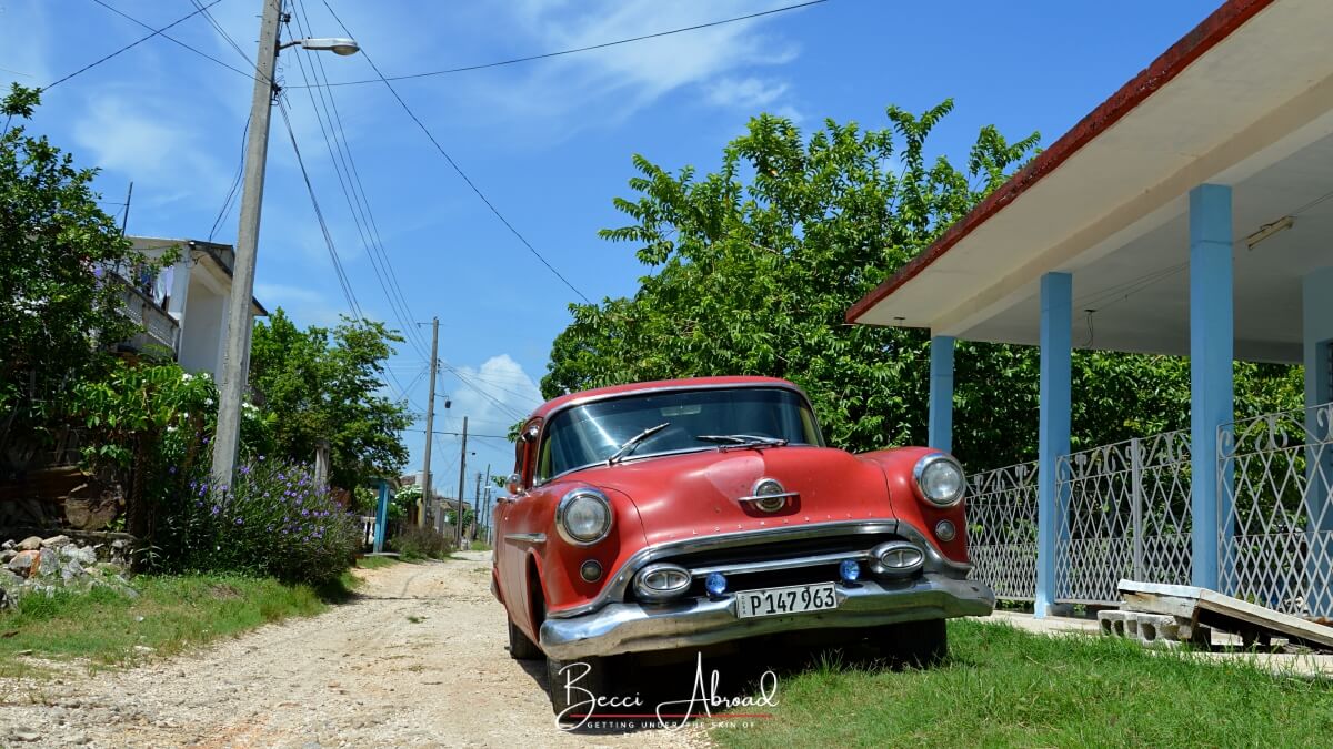 An red vintage American car parked on a street in rural Cuba - Traditional Cuban music is often about the life in the Cuban countryside