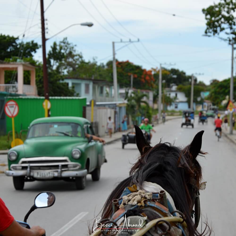 A horse and an old green vintage America car in the Cuban countryside