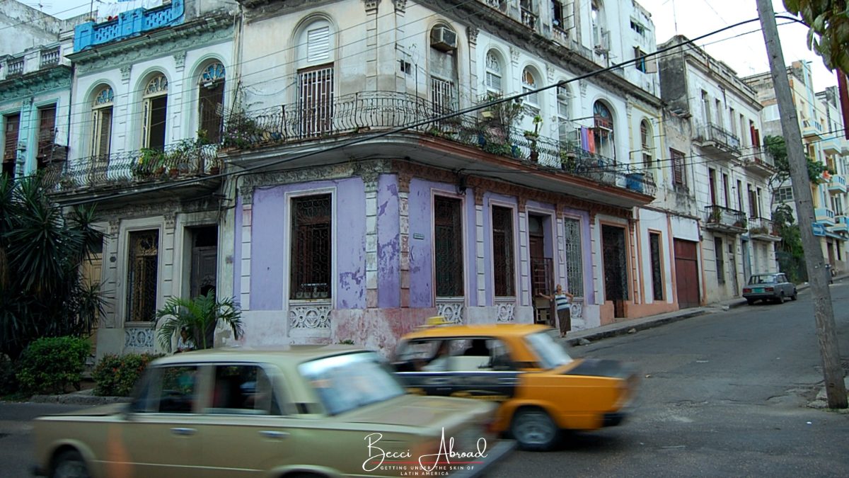 Cars driving by old colorful buildings in Centro Havana. Centro Havana is one of the best things to do in Havana to get a more authentic experience of Havana