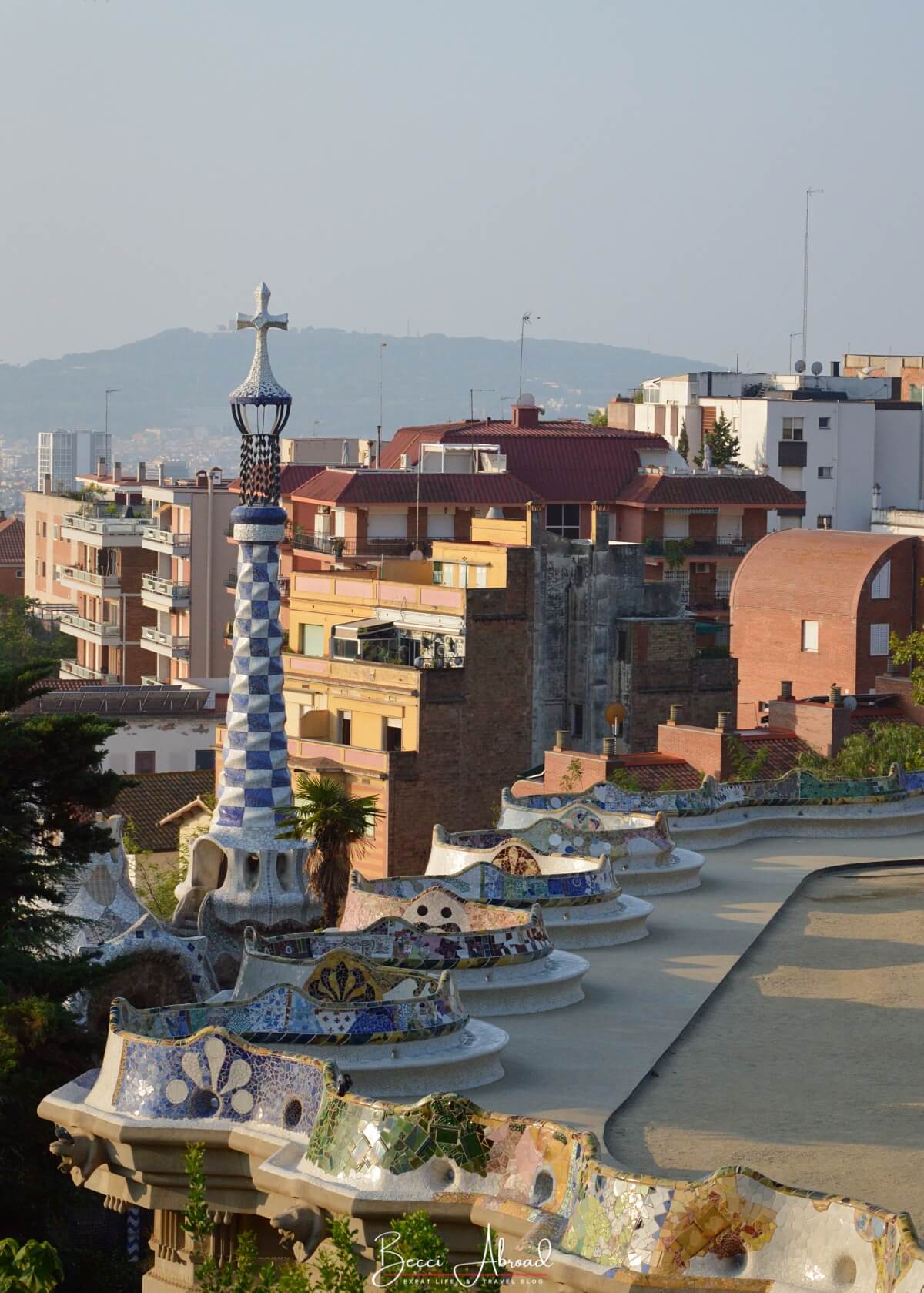 A wide view of the Monumental Zone in Park Güell, with the colorful benches encircling the open plaza overlooking Barcelona.