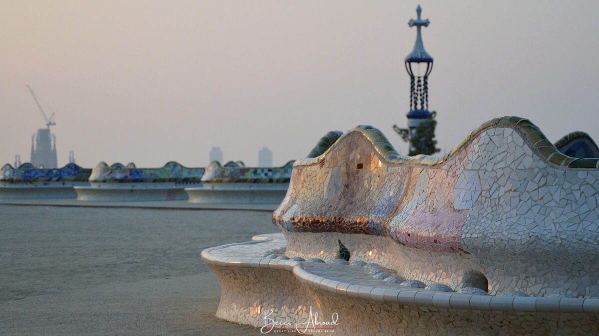 A close-up of the serpentine mosaic bench in Park Güell, wrapping around the edge of the upper plaza with views over Barcelona.