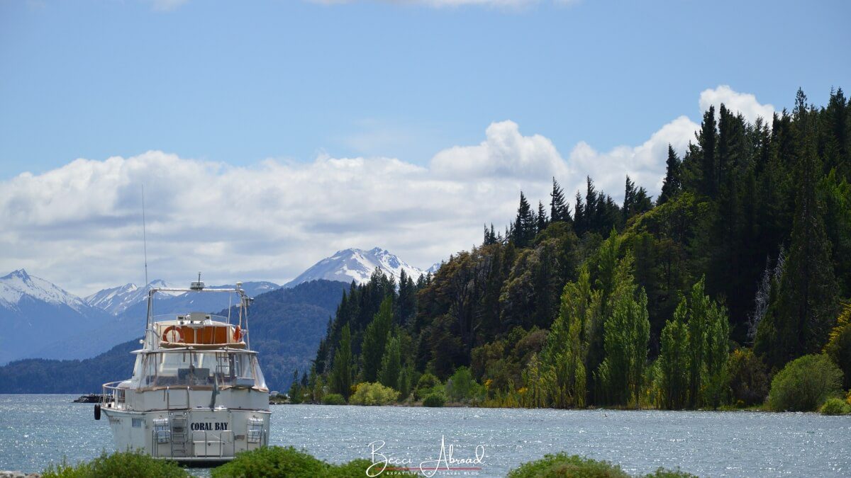 A boat on a lake in Bariloche with mountains and trees in the background