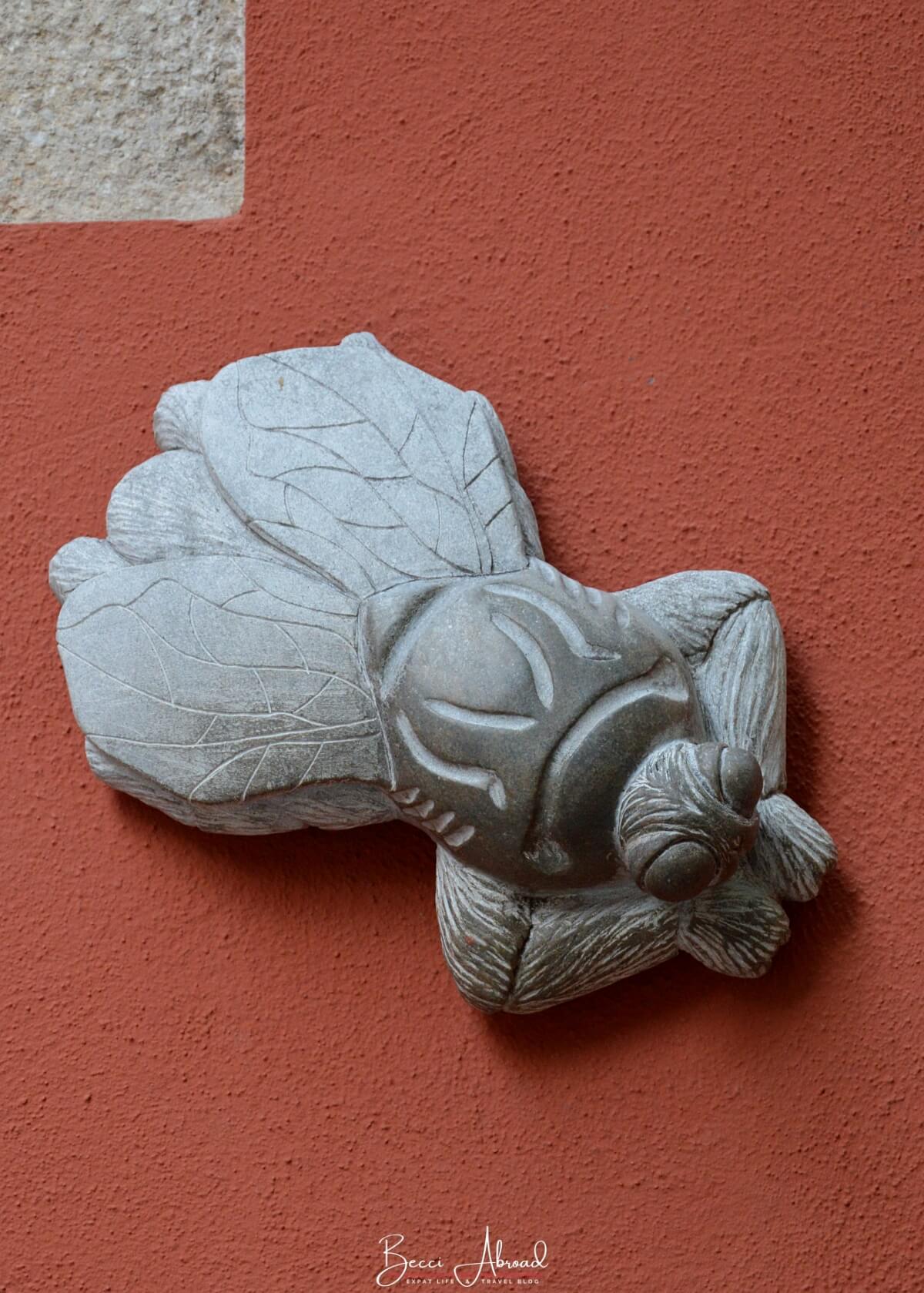 Fly statue on a red wall in Girona, Spain