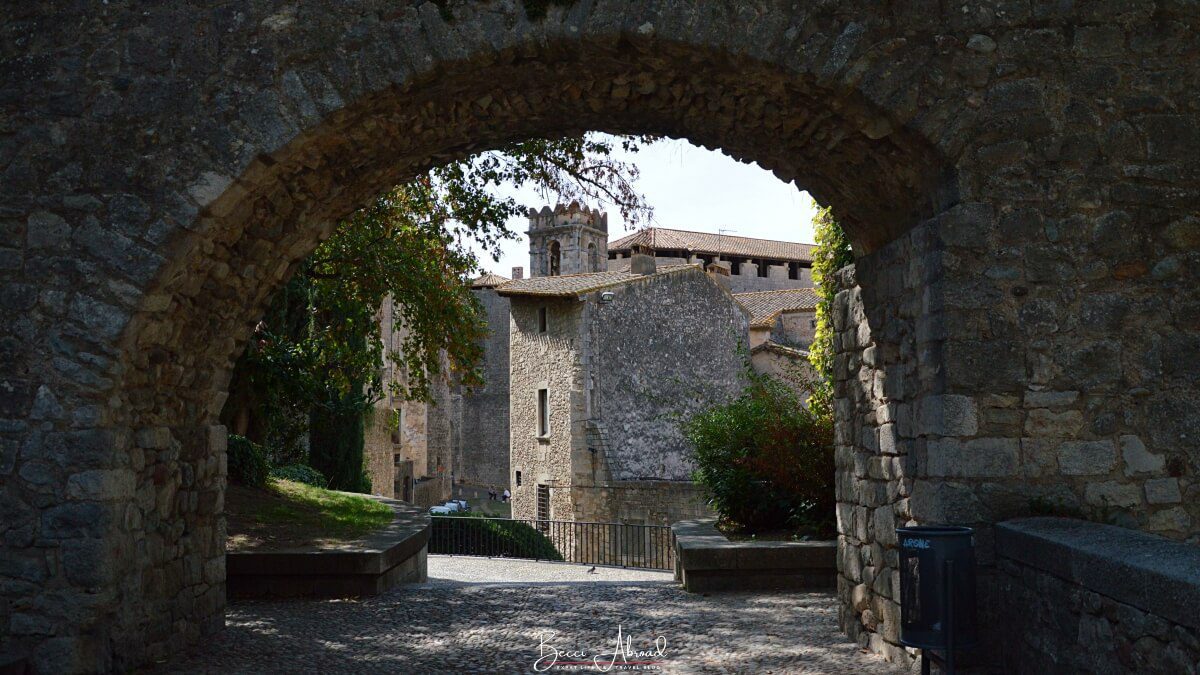 A cobblestone street in Girona's Old Town with historic stone buildings on either side