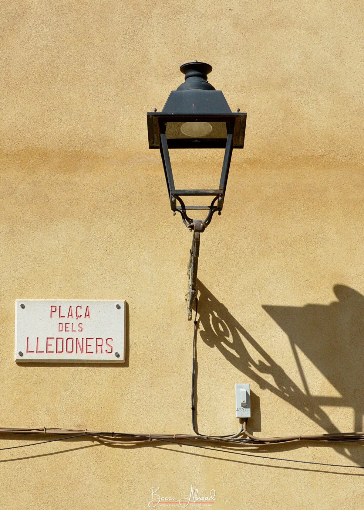 Old light stand hanging on a yellow wall in Girona