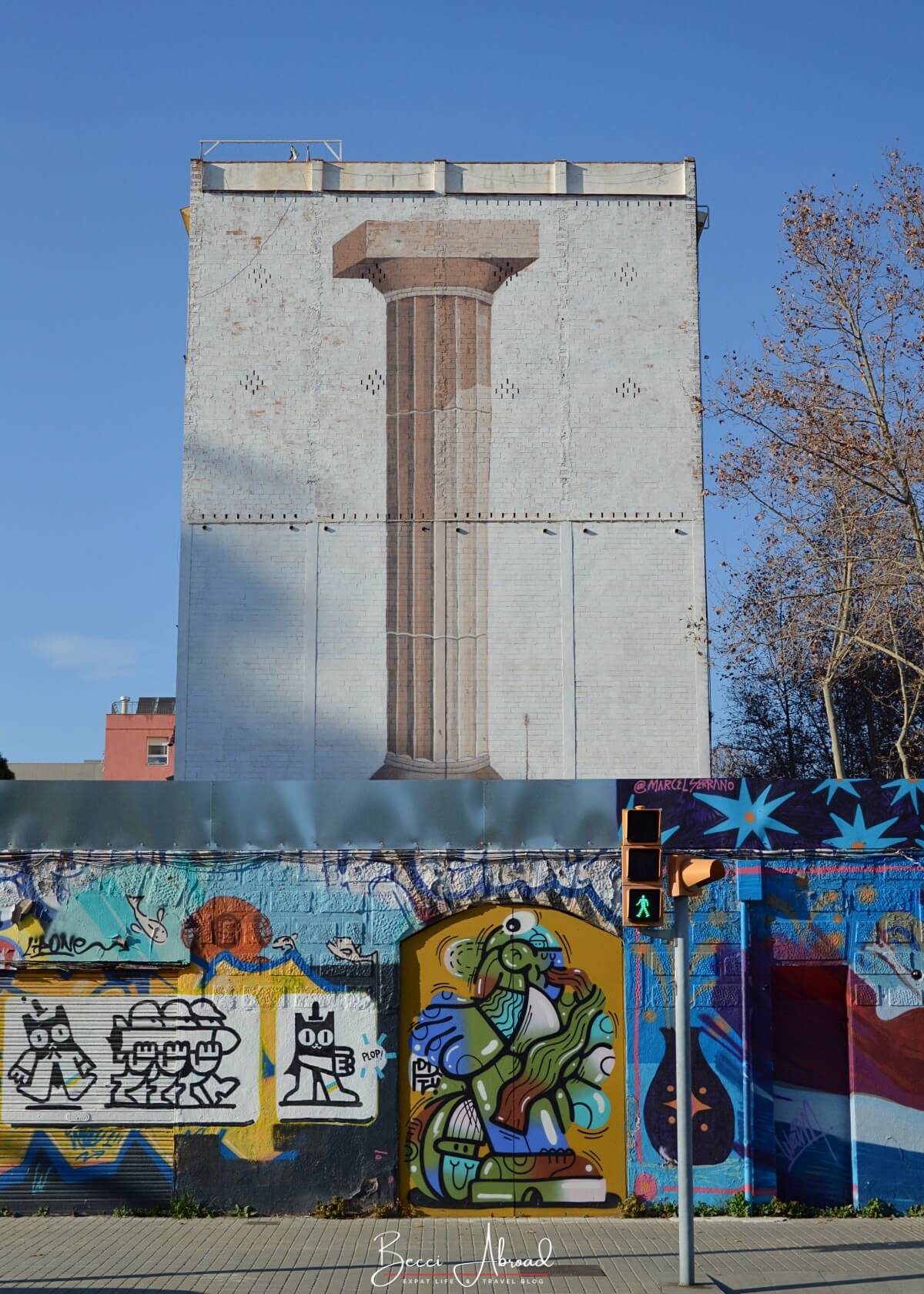 Colorful street art mural with a gigant mural of a Greek column in the background - Poblenou, Barcelona