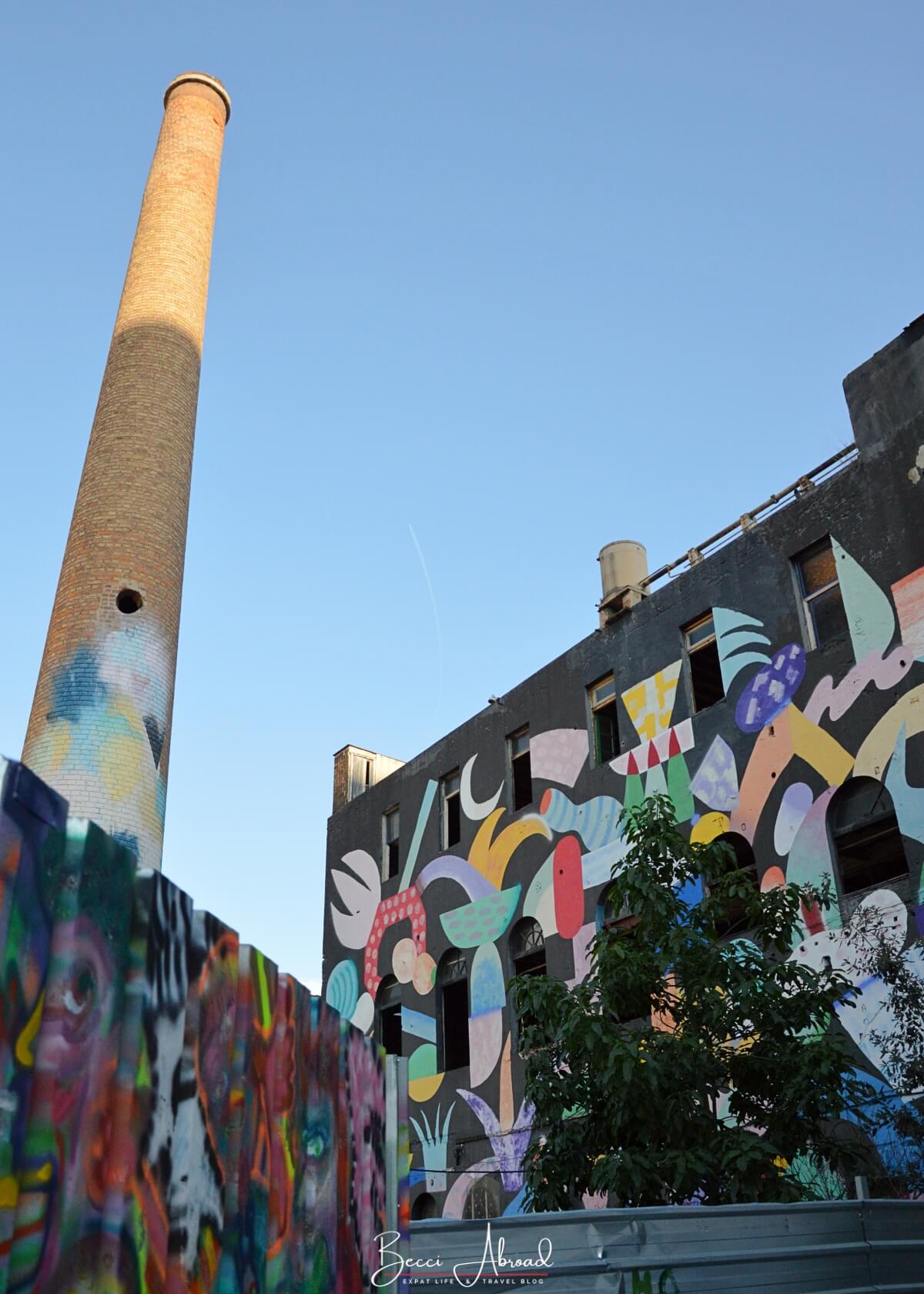 Colorful street art in Poblenou Barcelona with an old industrial tower in the background