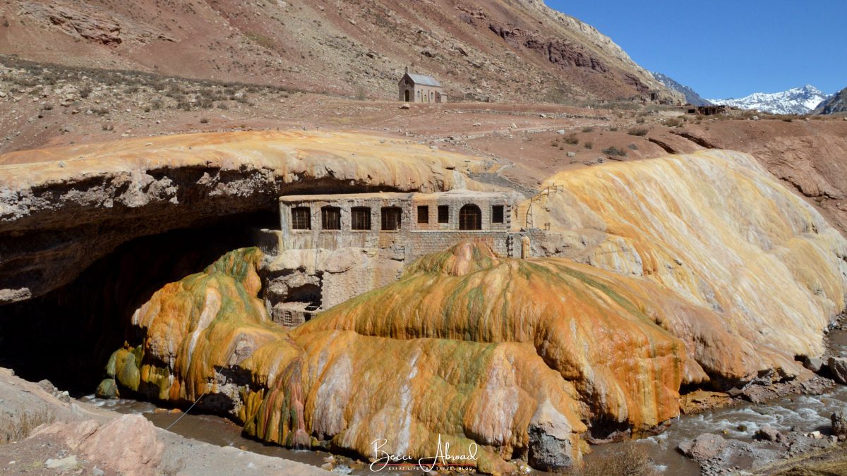 A scenic view of Puente del Inca surrounded by rugged Andean terrain and clear skies.