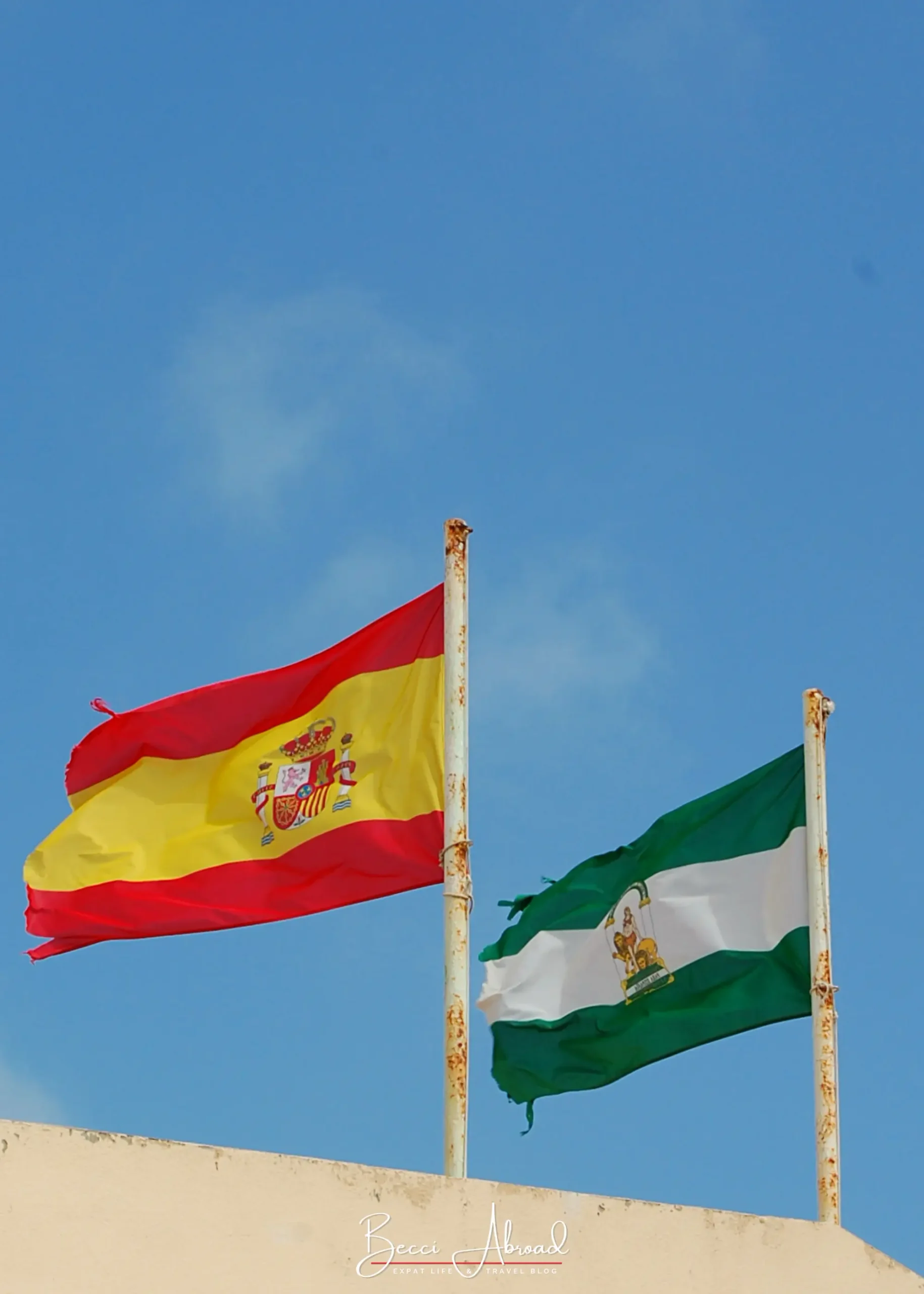 Spanish and Andalusian flags against a blue sky in Cádiz